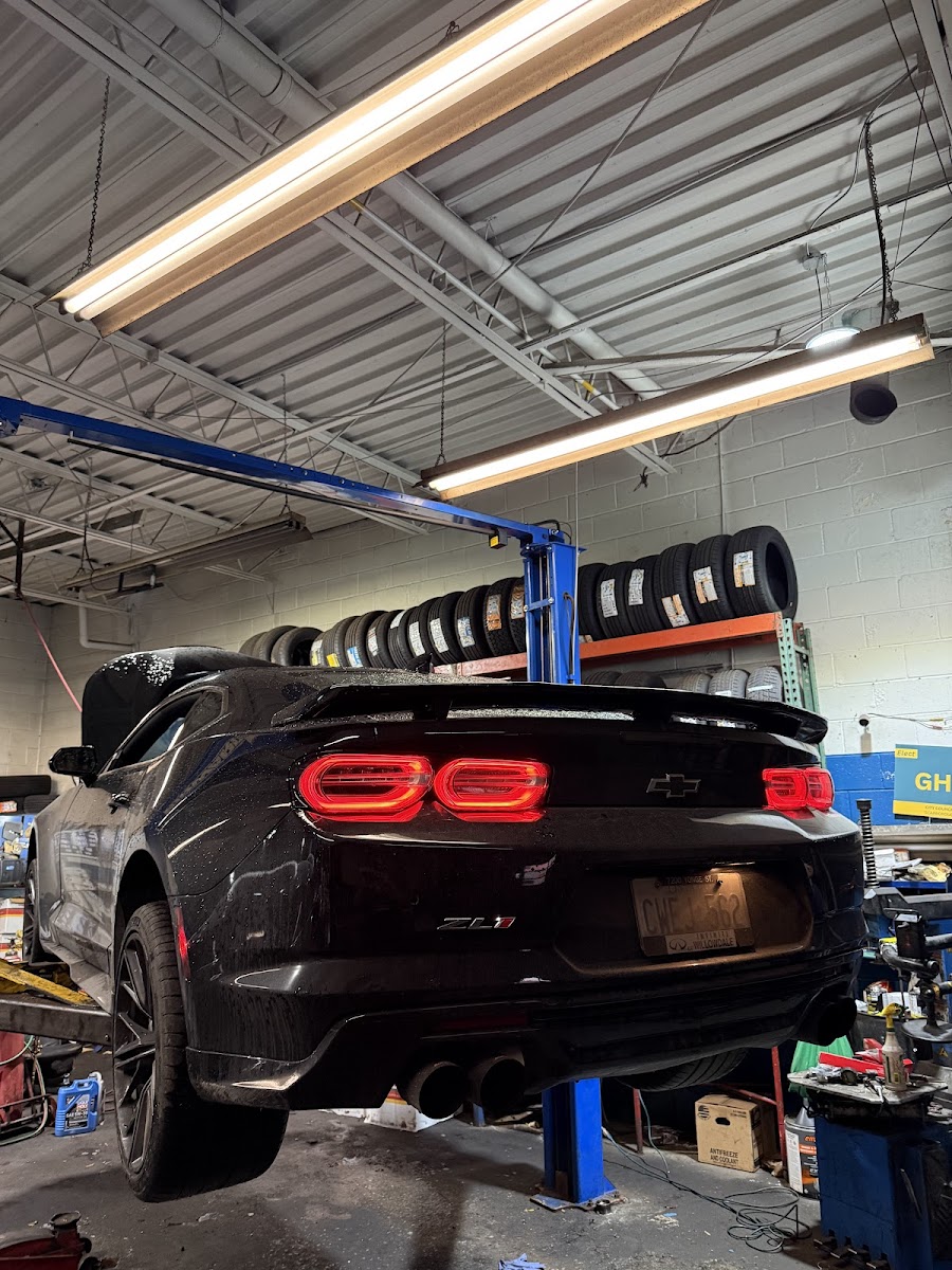 A black Camaro on the lift inside Active Auto Repairs & Sales, blue posts holding it up.